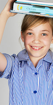 A girl reading a booklet wearing a bespoke school uniform